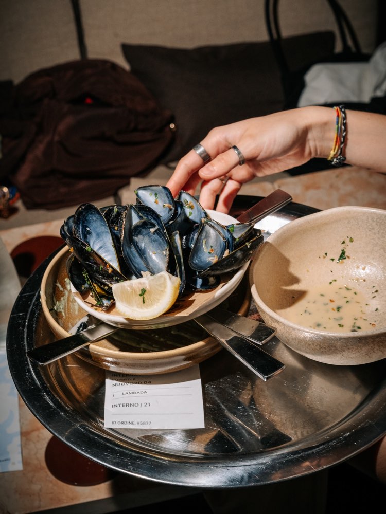 Cozze con limone e una ciotola di brodo, servite al tavolo